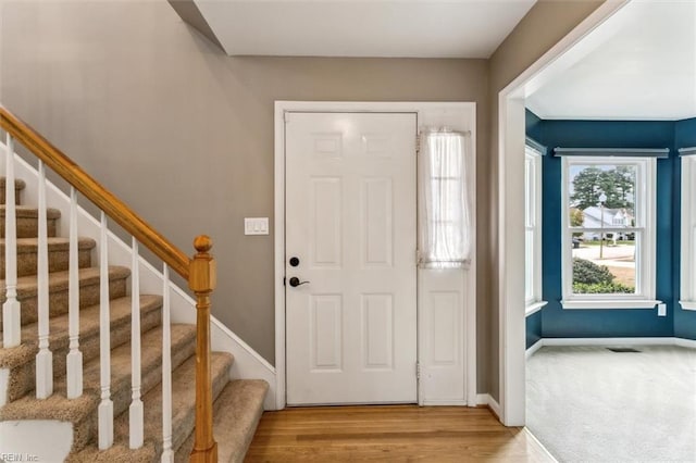 entrance foyer with light wood-style floors, stairway, and baseboards