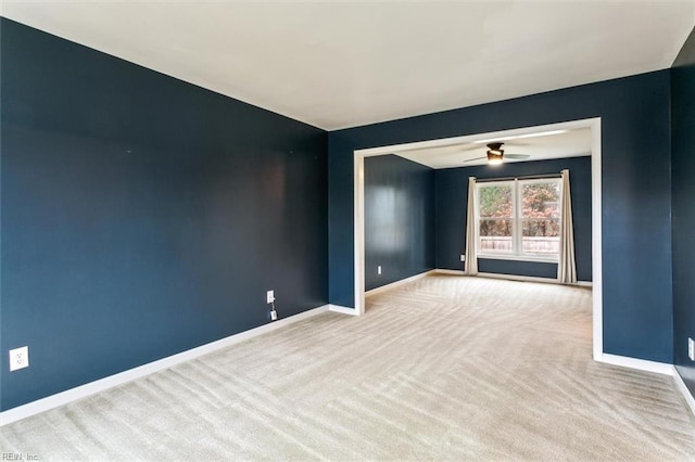 carpeted spare room with ceiling fan and baseboards