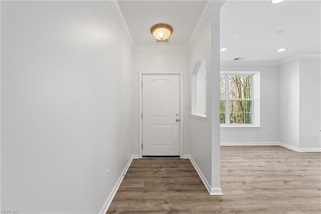 doorway with baseboards, ornamental molding, and wood finished floors