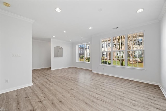 spare room featuring baseboards, light wood-style floors, visible vents, and crown molding