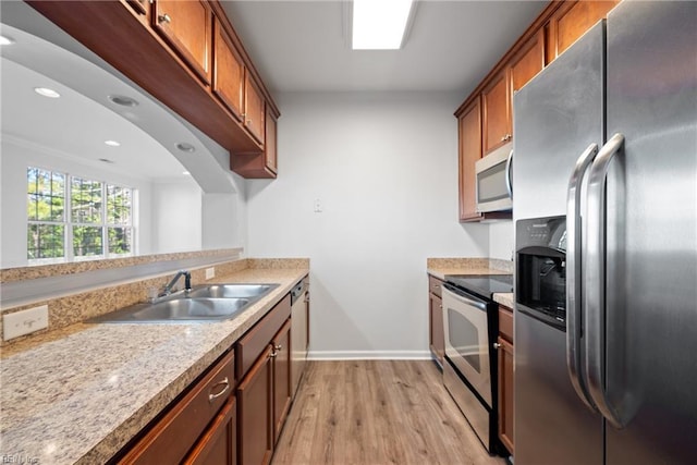 kitchen featuring light wood-style floors, appliances with stainless steel finishes, brown cabinetry, and light countertops