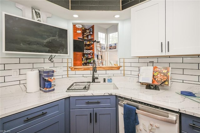 kitchen with decorative backsplash, white cabinetry, a sink, light stone countertops, and dishwasher