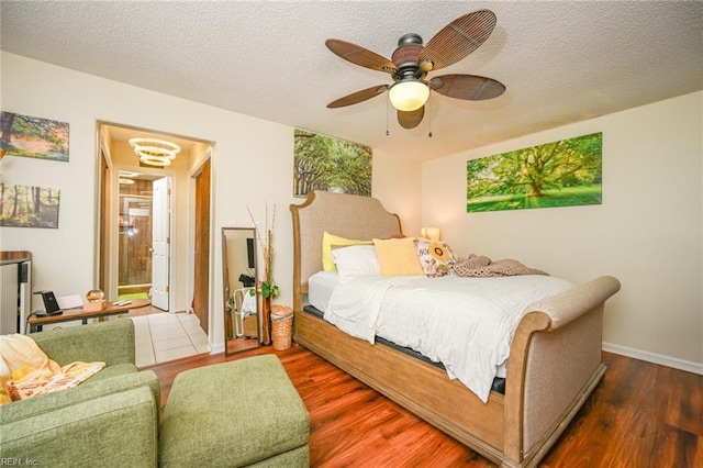 bedroom with ceiling fan, a textured ceiling, baseboards, and wood finished floors