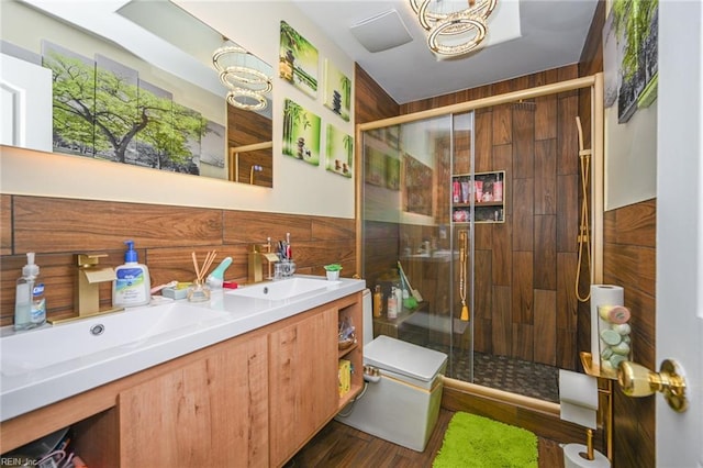 full bath featuring double vanity, a sink, a shower stall, and wood finished floors