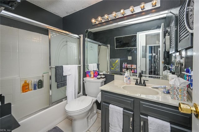 full bathroom featuring a textured ceiling, tile patterned flooring, toilet, bath / shower combo with glass door, and vanity