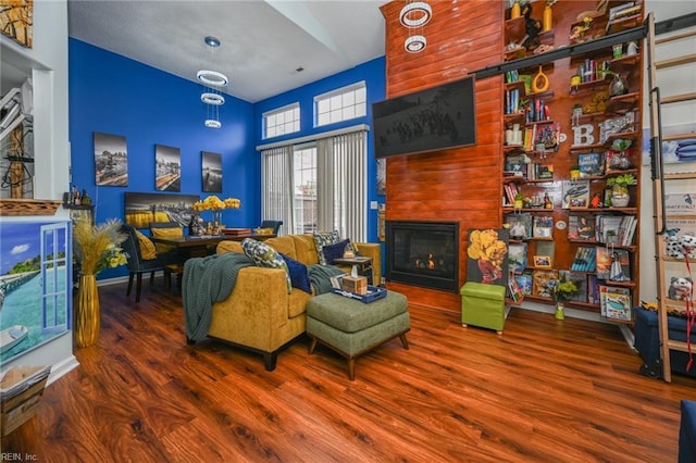 sitting room featuring a large fireplace, wood finished floors, a towering ceiling, visible vents, and baseboards