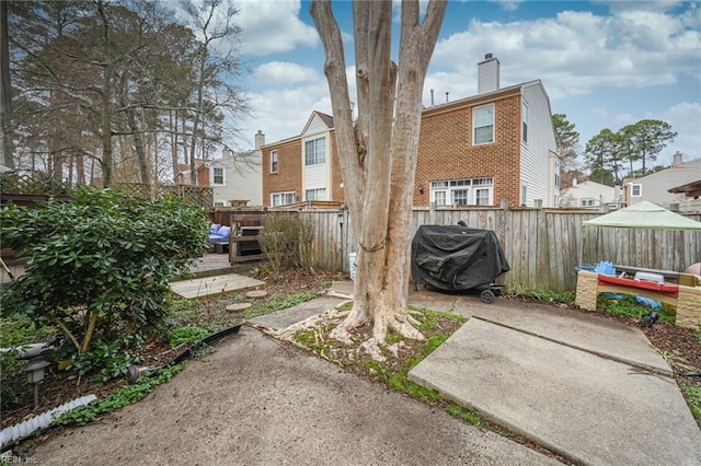 view of yard featuring a residential view, fence, a wooden deck, and a patio