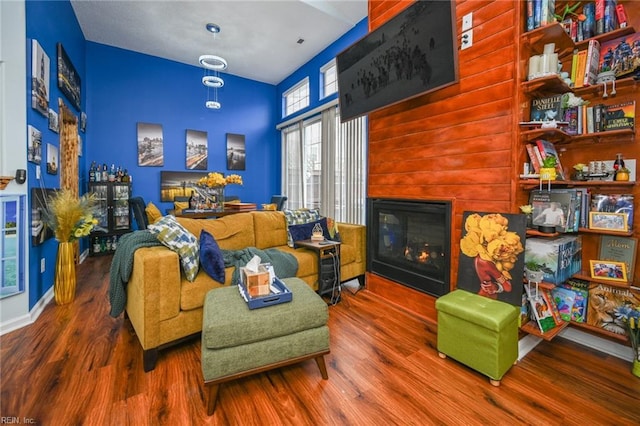 sitting room featuring a glass covered fireplace, baseboards, and wood finished floors