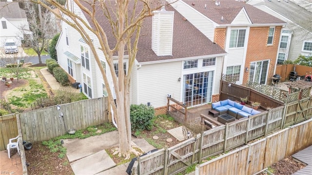 rear view of property featuring a fenced backyard, a residential view, an outdoor living space, and roof with shingles