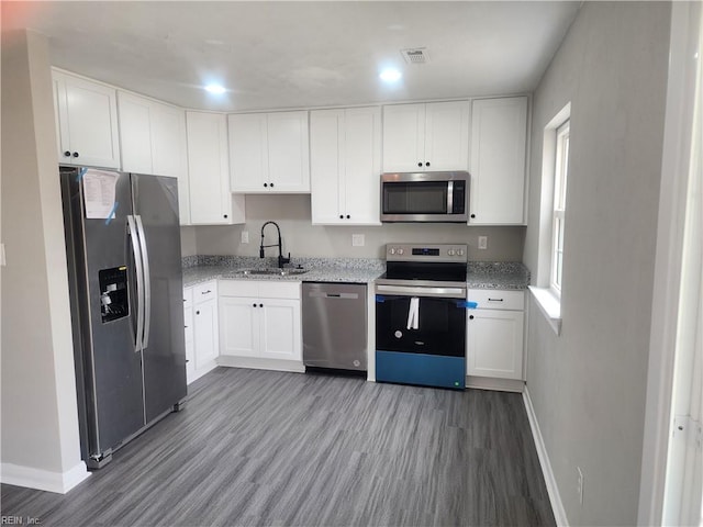 kitchen with appliances with stainless steel finishes, a sink, light wood-style floors, and white cabinets