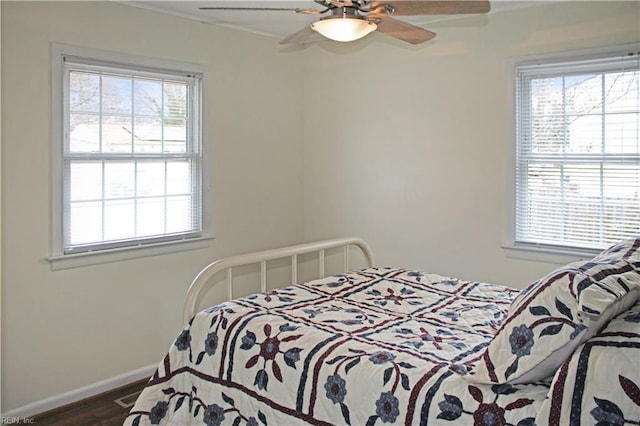 bedroom with a ceiling fan, multiple windows, wood finished floors, and baseboards