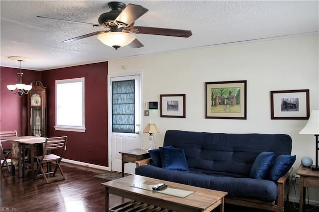 living room with ceiling fan with notable chandelier, wood finished floors, baseboards, and a textured ceiling