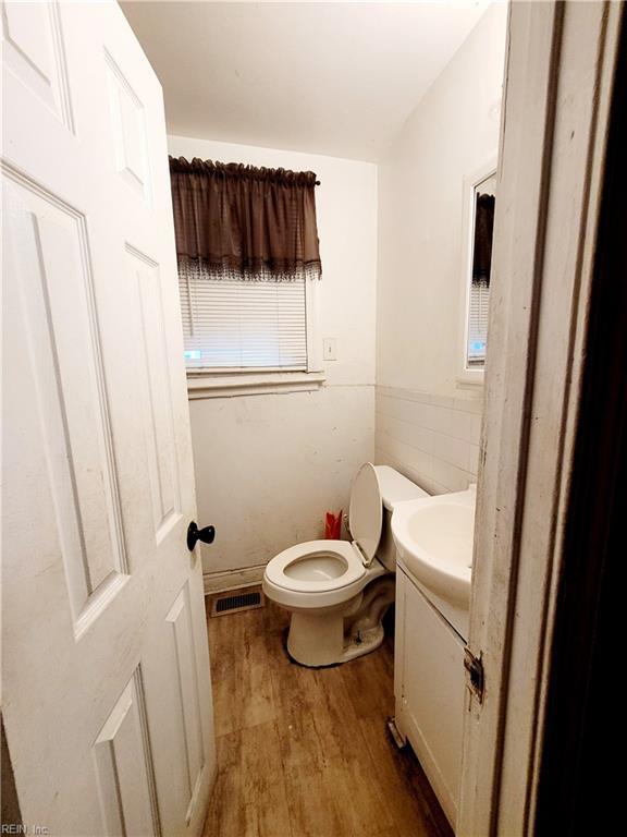 bathroom featuring tile walls, visible vents, toilet, vanity, and wood finished floors