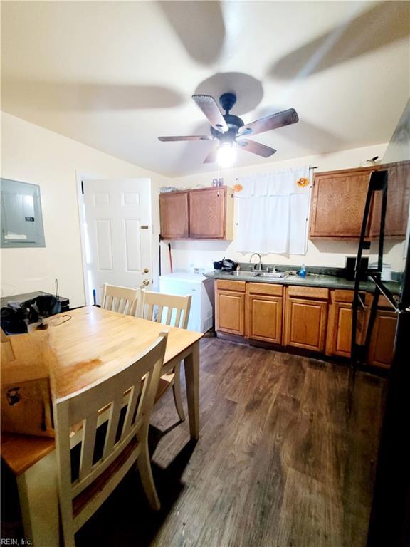 kitchen featuring electric panel, dark wood finished floors, a ceiling fan, brown cabinets, and a sink