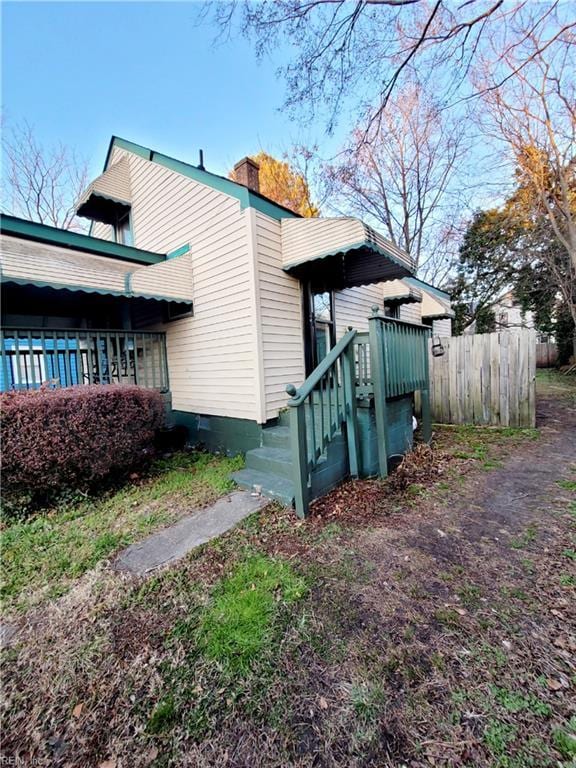 view of side of home featuring a chimney and fence