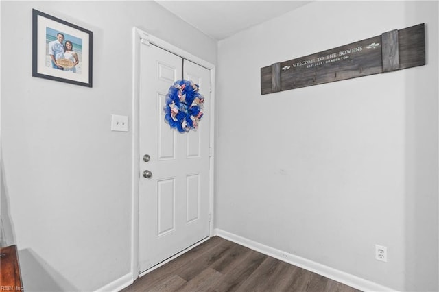 foyer entrance with dark wood-style floors and baseboards