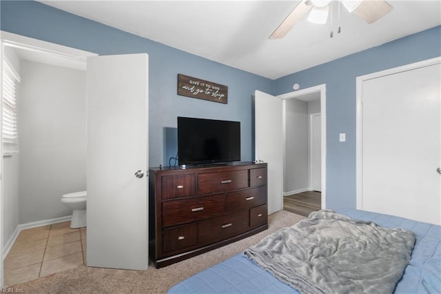 bedroom with light tile patterned floors, baseboards, light colored carpet, ensuite bath, and ceiling fan