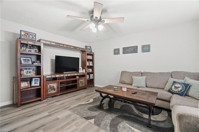 living room featuring ceiling fan, baseboards, and wood finished floors