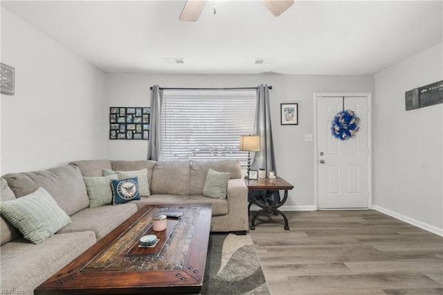 living room with a ceiling fan, visible vents, baseboards, and wood finished floors