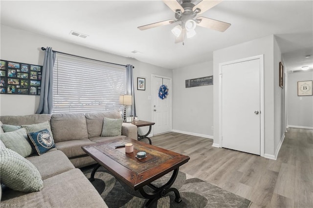 living room featuring visible vents, ceiling fan, baseboards, and wood finished floors