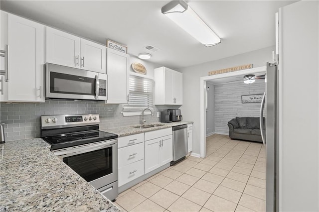 kitchen with stainless steel appliances, backsplash, a sink, and white cabinets