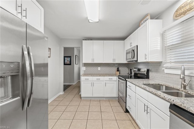 kitchen with light tile patterned floors, decorative backsplash, appliances with stainless steel finishes, white cabinetry, and a sink