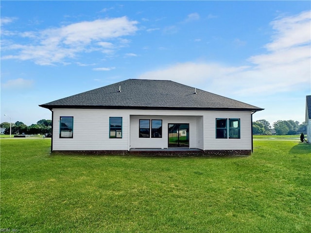 back of house featuring roof with shingles and a yard