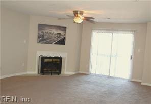 unfurnished living room with carpet flooring, a glass covered fireplace, a ceiling fan, and baseboards