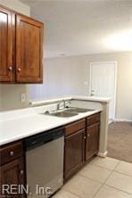 kitchen featuring light countertops, a sink, stainless steel dishwasher, and light tile patterned floors