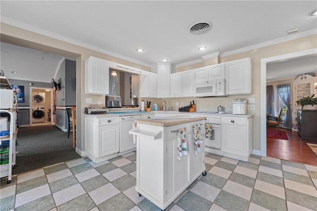 kitchen featuring stacked washer / drying machine, white appliances, white cabinets, and light countertops