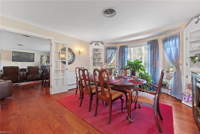 dining space with hardwood / wood-style floors, visible vents, and ornamental molding