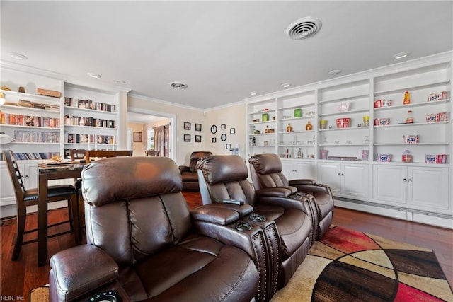 cinema featuring built in features, visible vents, wood finished floors, and crown molding