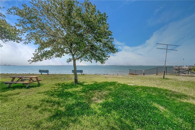 view of property's community featuring a lawn, fence, and a water view