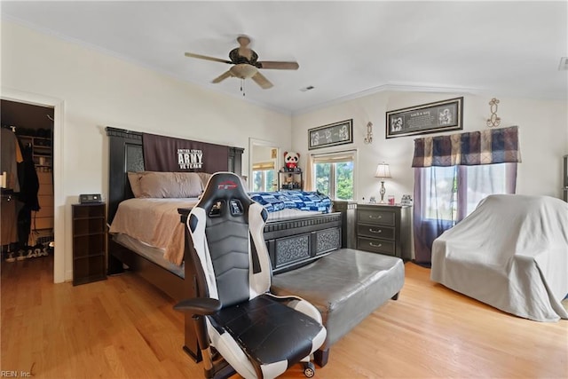 bedroom featuring a spacious closet, visible vents, light wood finished floors, and ornamental molding