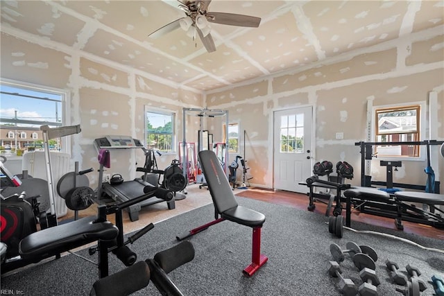 exercise room featuring wood finished floors, plenty of natural light, coffered ceiling, and ceiling fan