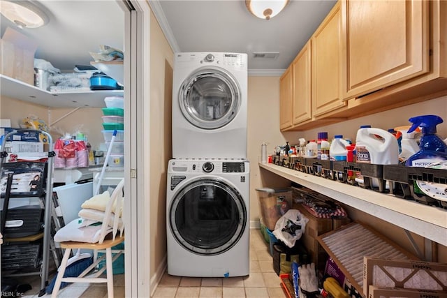 laundry area featuring light tile patterned floors, visible vents, stacked washer and clothes dryer, and ornamental molding