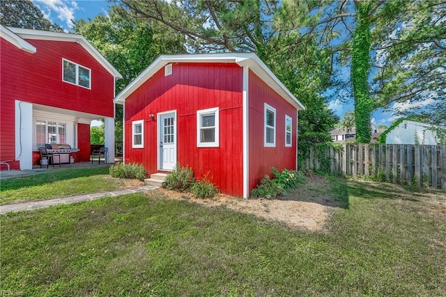 view of outbuilding featuring entry steps, an outdoor structure, and fence