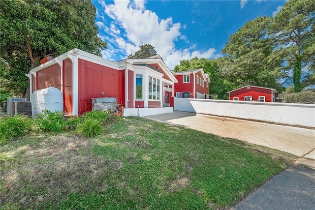 exterior space featuring cooling unit, a patio, a front lawn, and fence