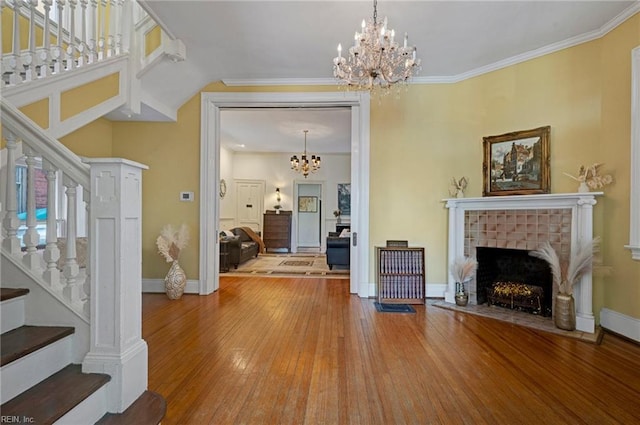 living area with a chandelier, wood-type flooring, crown molding, and stairway