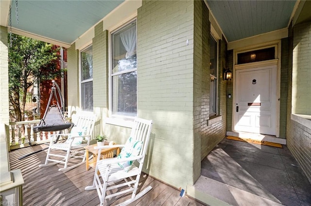 property entrance featuring a porch and brick siding