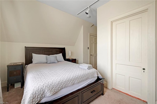 bedroom with lofted ceiling, light colored carpet, and rail lighting