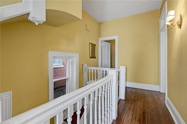 hallway featuring baseboards, an upstairs landing, and wood finished floors