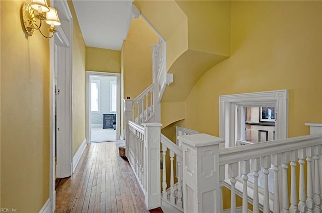 hall with baseboards, hardwood / wood-style floors, and stairs