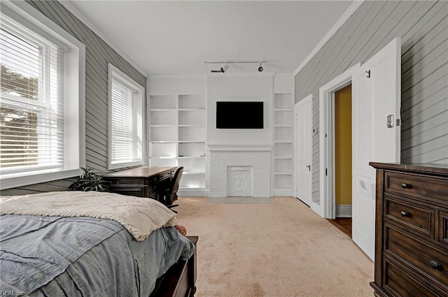 carpeted bedroom with ornamental molding, multiple windows, a fireplace, and wooden walls