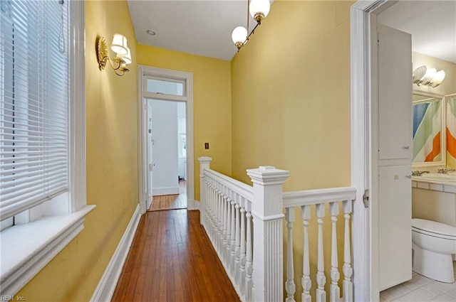 hallway with hardwood / wood-style flooring, baseboards, and an upstairs landing