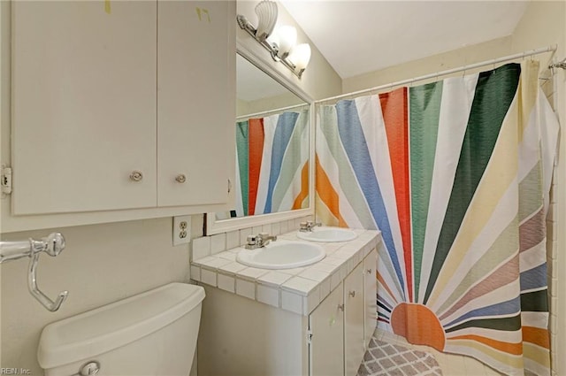 full bathroom with curtained shower, a sink, toilet, and double vanity