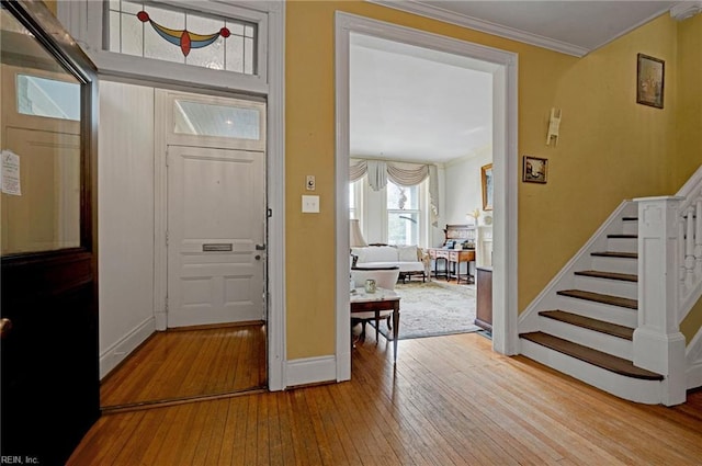 foyer entrance with crown molding, stairway, baseboards, and hardwood / wood-style flooring