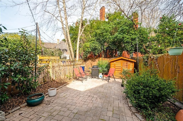 view of patio / terrace with an outbuilding, a fenced backyard, and a grill