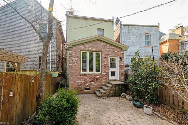 back of house featuring brick siding, crawl space, a patio area, and a fenced backyard