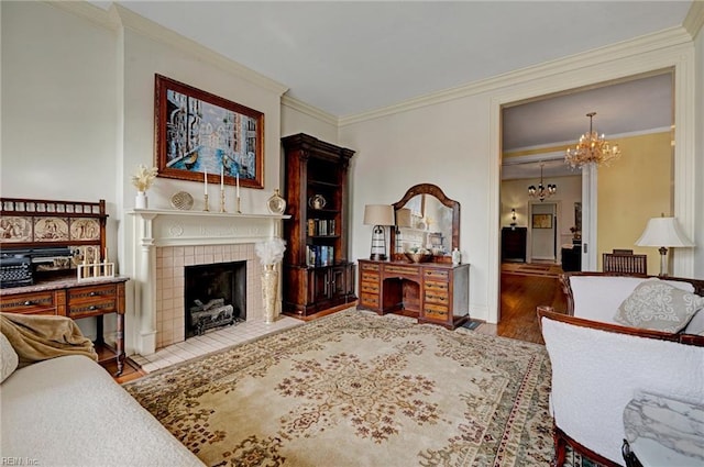 living room with crown molding, wood finished floors, a tile fireplace, and a notable chandelier